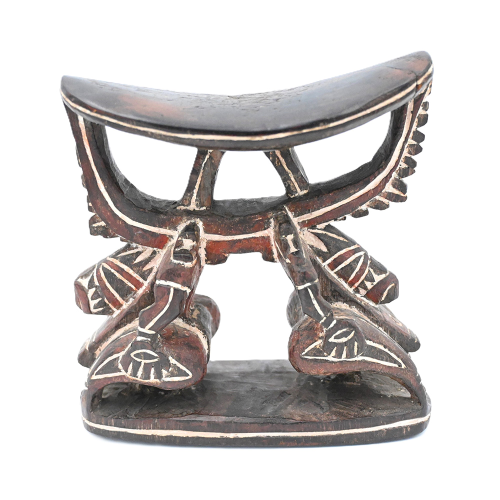 wooden headrest with abstract human figures forming supports