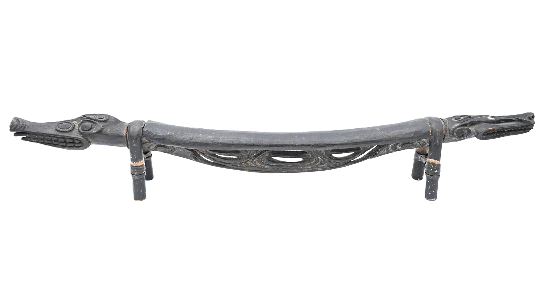 long wooden headrest with crocodile heads on each end
