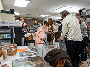 College students looking at a man holding an artifact