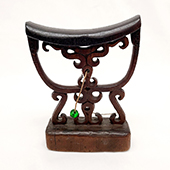 Carved wooded headrest with green bead attached
